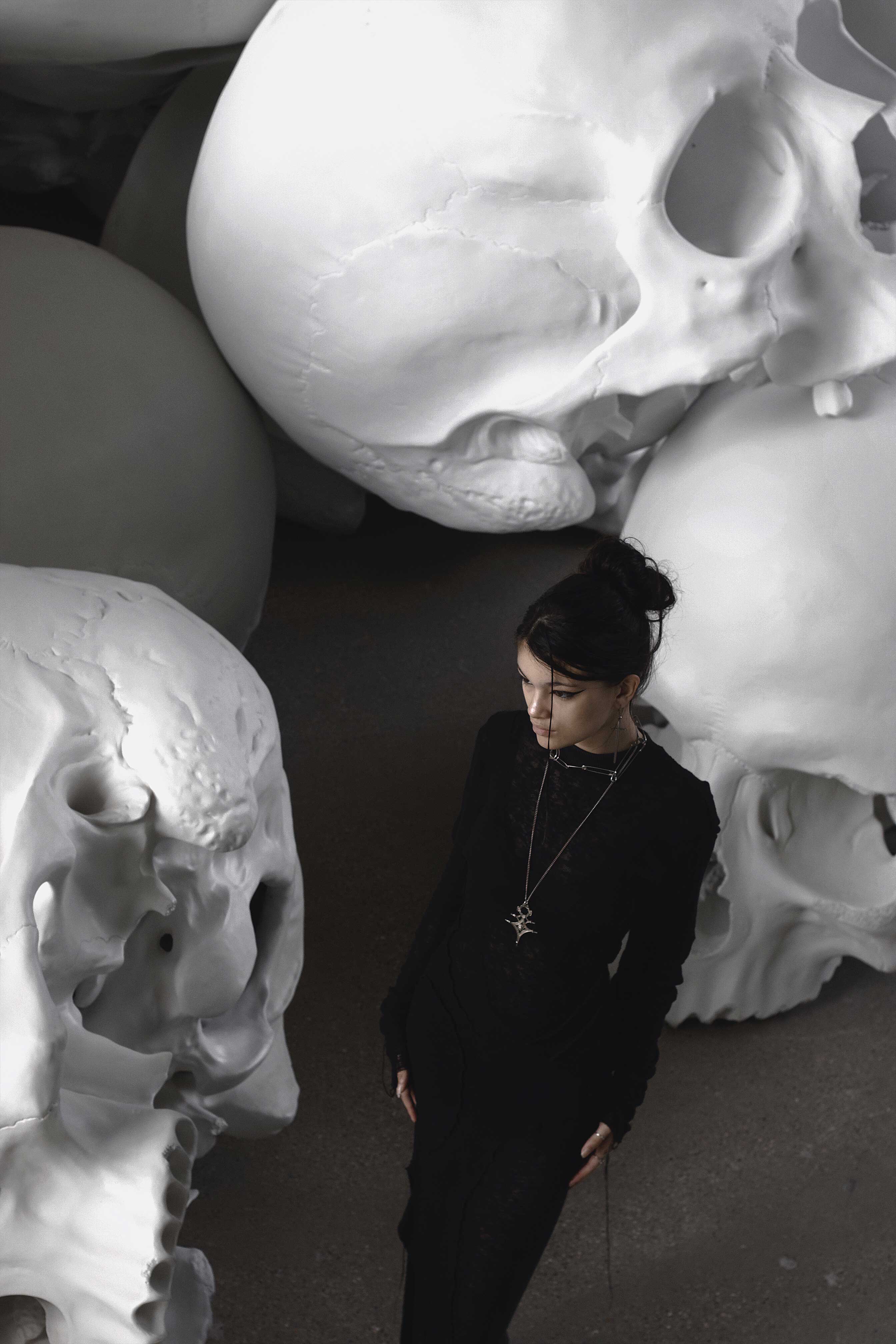 photo of a girl standing in front of a pile of skull