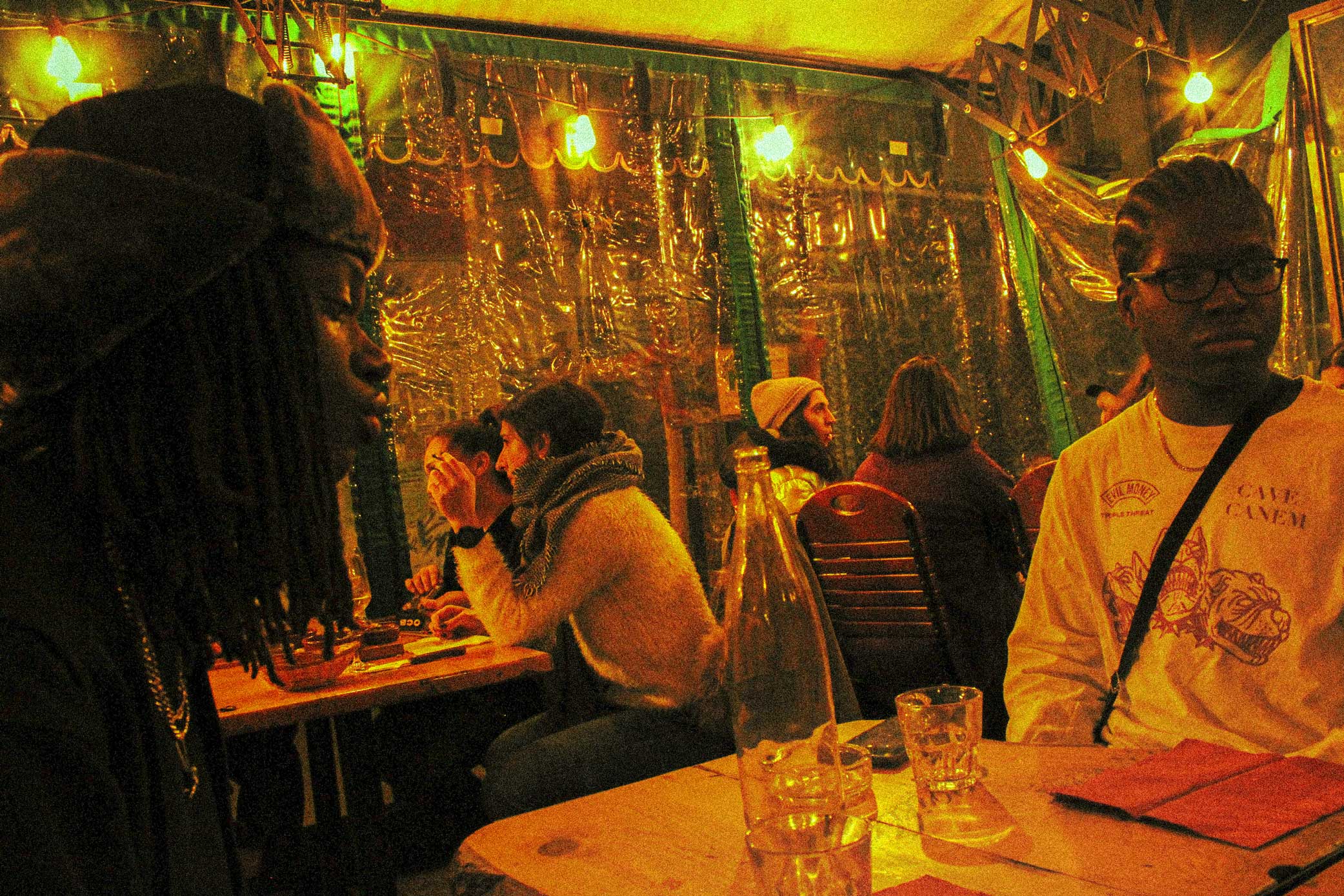 two men in a cafe, a cold autumn evening, the lights are yellow and orange. the athmosphere feels warm