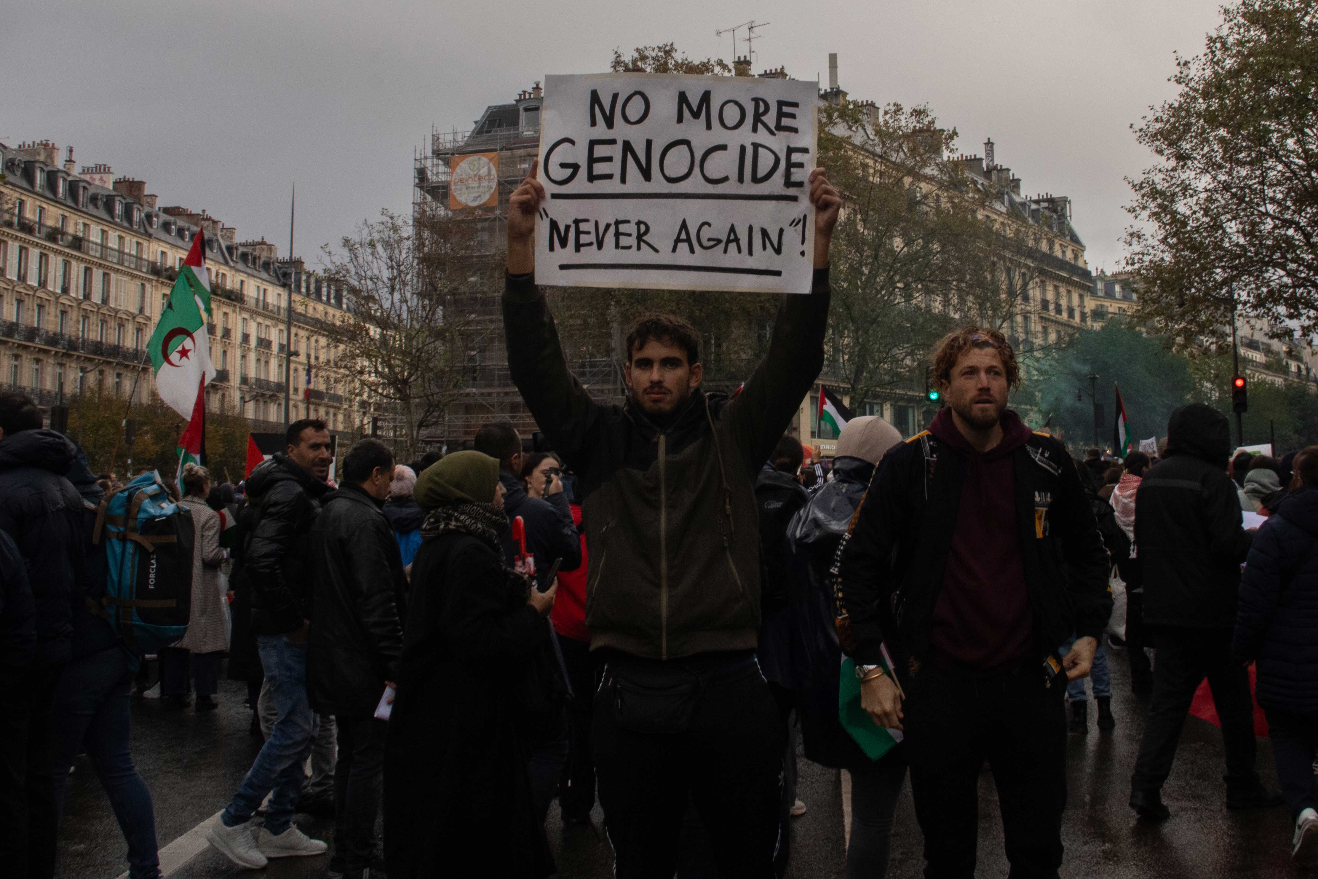 photo of a man showing a sign written no more genocide, never again for a protest to stop the genocide of palestinian