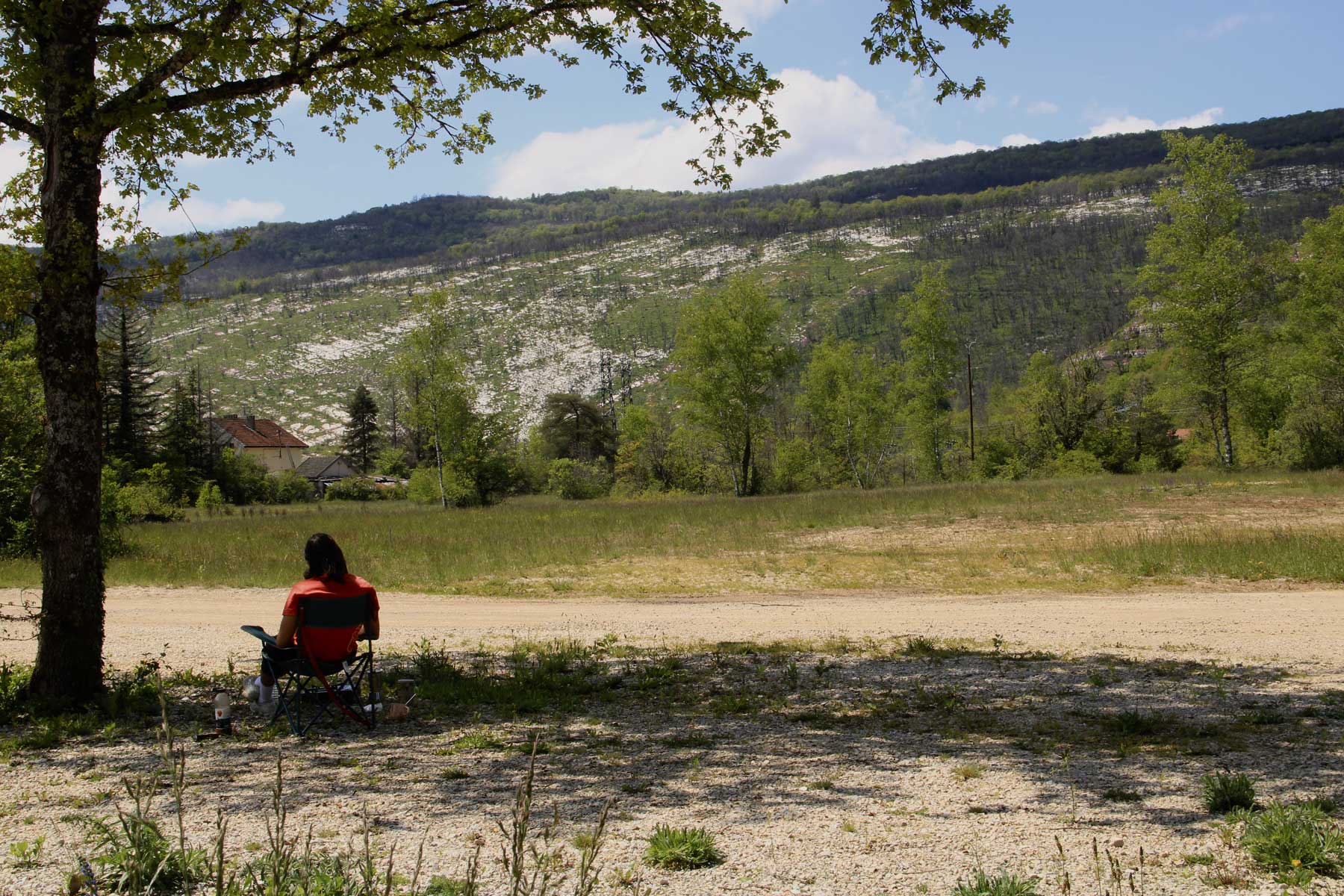 photo of a landscape in Vouglans, France. A man is sitting on a chair admiring the view